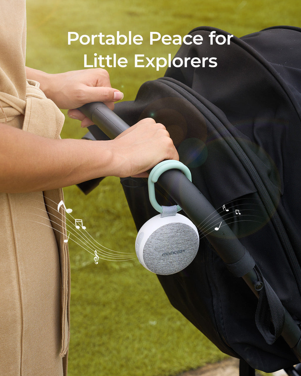 Momcozy portable sound machine attached to stroller, providing peace with white and gray speaker and green handle.