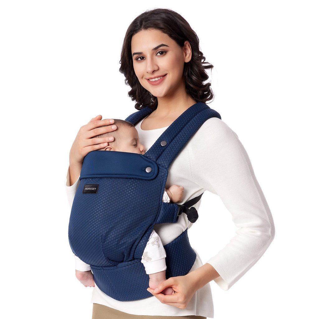 Momcozy PureHug baby carrier in navy blue. Mother comfortably babywearing, ergonomic design for newborns.