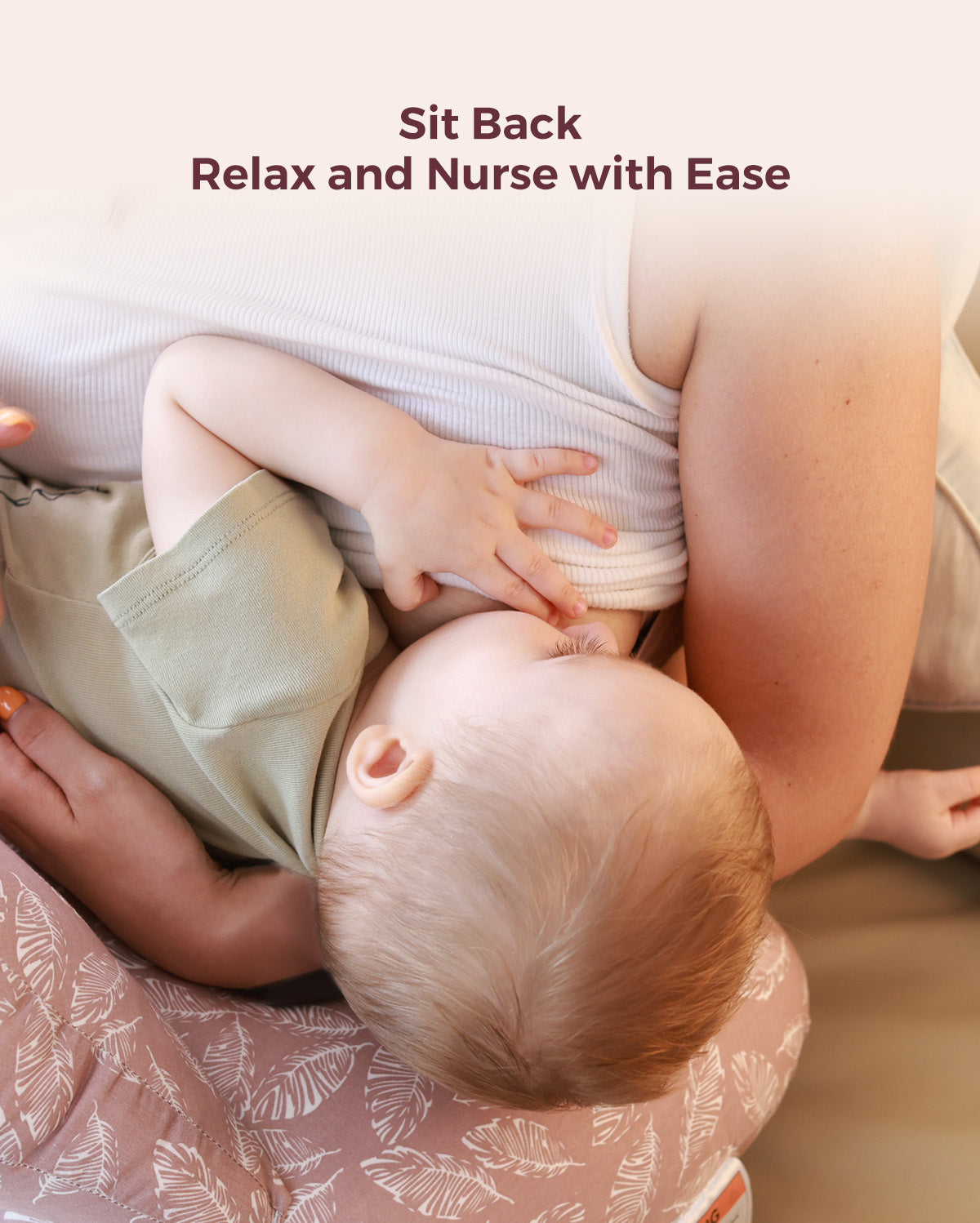 Multifunctional nursing pillow, adjustable, pink leaf pattern. Supports comfortable breastfeeding. Text: Sit Back Relax and Nurse with Ease.