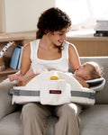 Momcozy memory foam nursing pillow supporting baby, white with bottle pocket.